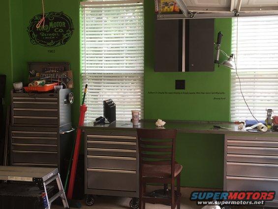 Garage workbench with tool chests, a chair, and a Ford Motor Co. logo on the wall