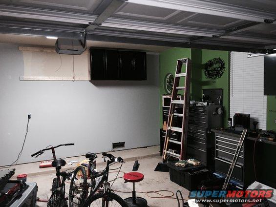 Garage interior with two bicycles, a ladder, tool chests, and storage cabinets