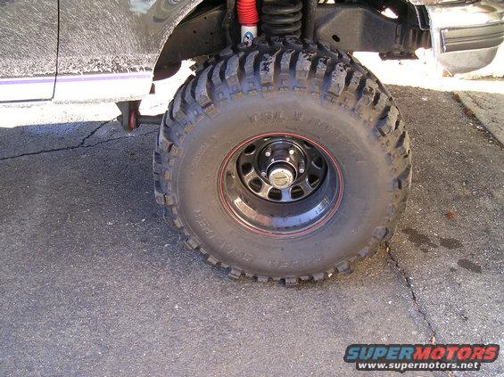 Truck tire with red rim, red shock absorber visible