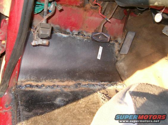 Interior floor pan repair with visible welds and pedals