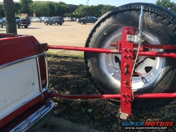 Bent a CB Antenna mirror mount and attached to the spare tire holder.