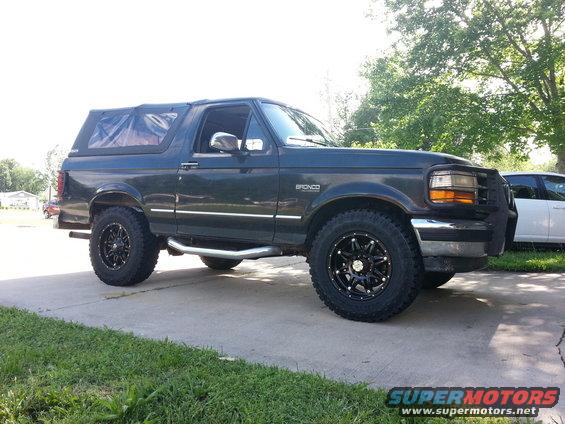 Dark green 1994 Ford Bronco side view with aftermarket wheels and brush guard