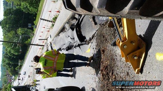 workers near a collapsed road section with heavy equipment nearby