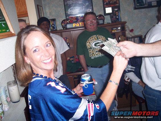 Woman in a blue jersey holds a can and money is exchanged between hands