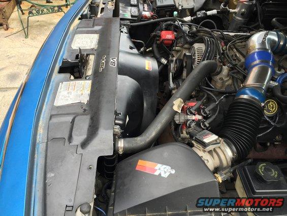 Engine bay with V8 badge and K&N air filter. Blue exterior visible
