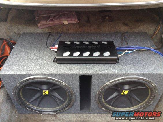 Car trunk interior with a dual Kicker subwoofer box and an Audiopipe amplifier. A folded towel is visible in the upper left
