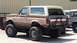 1988 Ford Bronco - This lifted two-tone brown SUV appears to be a 1987 Ford Bronco, modified with large off-road tires.
