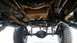 1988 Ford Bronco - The underside of a modified off-road vehicle reveals its heavy-duty suspension and drivetrain components.