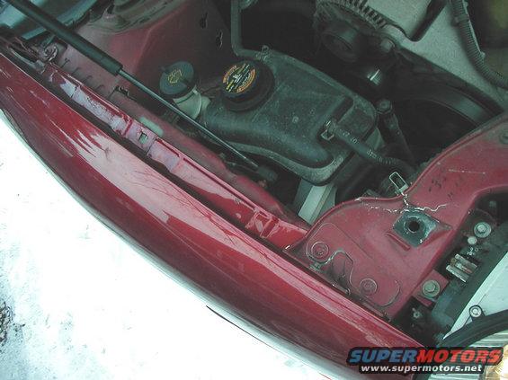 close-up of red car engine bay, showing coolant reservoir and alternator