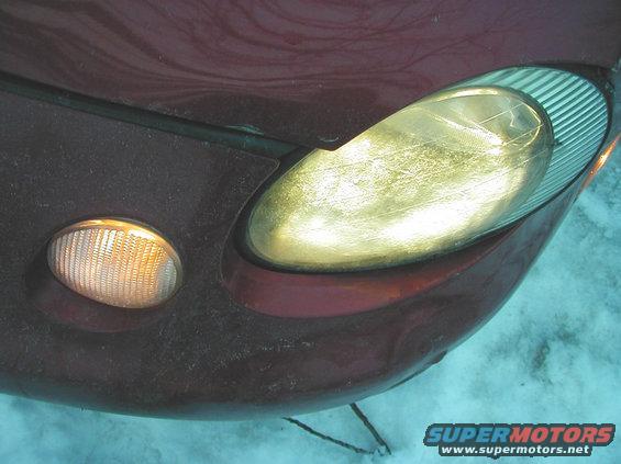 close-up of a car's front corner showing a headlight and amber turn signal