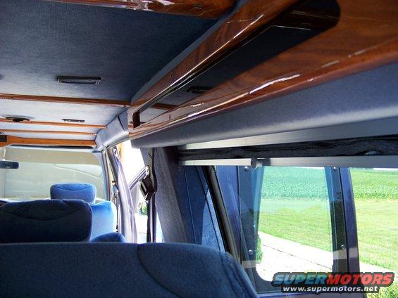 Interior of a van with blue upholstered seats and wood trim on the ceiling