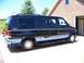 2000 Ford E150 - This van features a two-tone paint scheme with silver and light blue accents along the lower body.