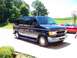 2000 Ford E150 - A dark blue van with silver trim is parked on a driveway next to a red car.