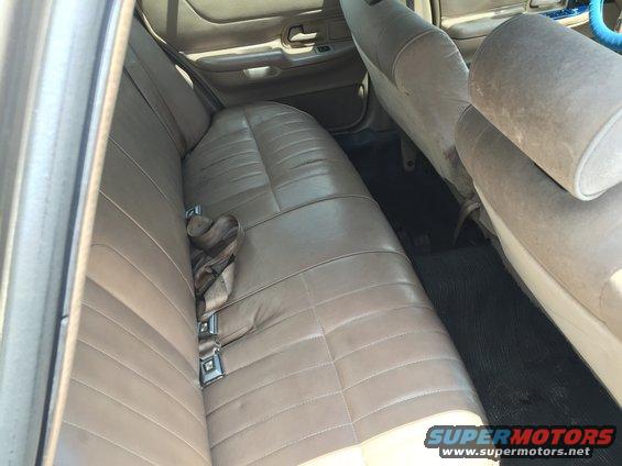 Back seat and interior of a car, showing tan leather seats and seatbelts