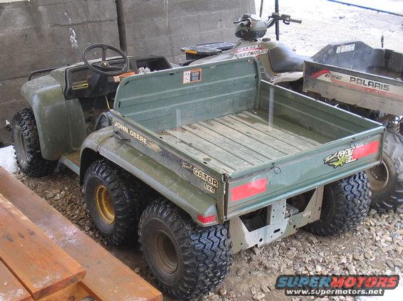 John Deere Trail Gator 6x4 utility vehicle parked next to an ATV and a Polaris utility vehicle