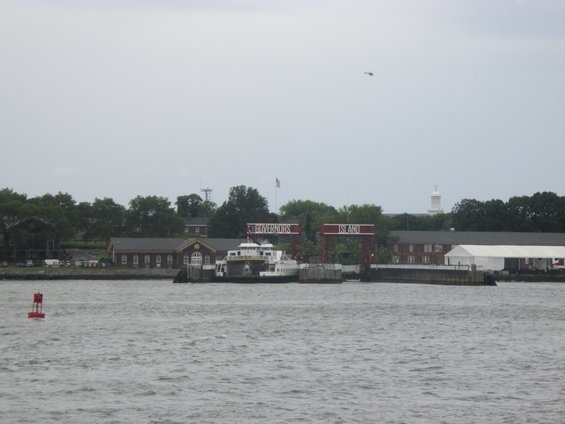 Governors Island ferry terminal with a ferry docked and a helicopter flying overhead