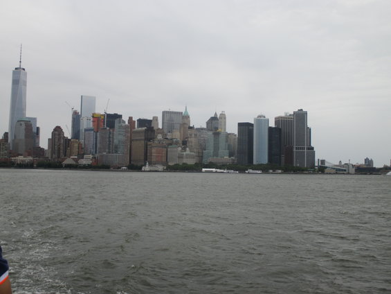 New York City skyline with One World Trade Center and other skyscrapers across the water under a cloudy sky