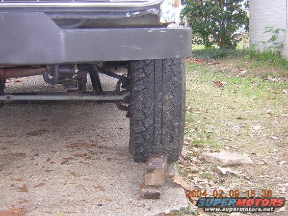 Front wheel and suspension components of a vehicle, with the wheel resting on a block