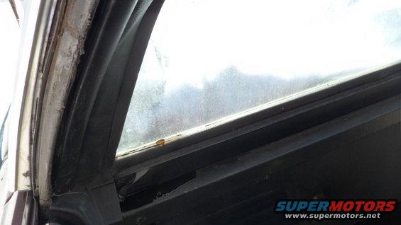 Close-up of a car's interior window frame and seal, showing wear and tear