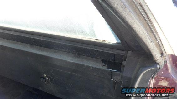 Close-up of a car's interior door frame and window seal. Shows some wear and tear