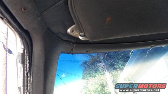 Interior view of a car's headliner and sun visor, showing wear and tear