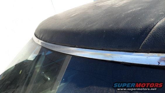Close-up of a black convertible top edge with chrome trim above the windshield