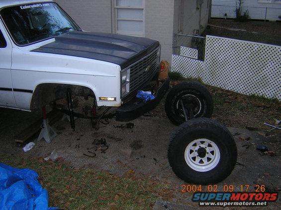 White 1981 Chevrolet K5 Blazer front end on jack stands, hood open, front wheels removed