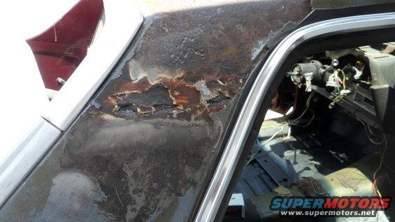 rusted out roofline above the door and the stripped interior of a car