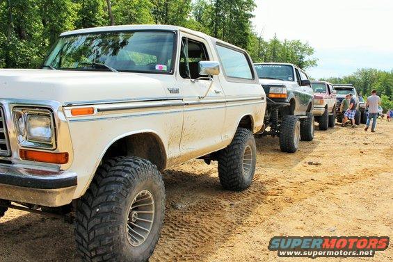 White 1978 Ford Bronco with large tires, parked on dirt road