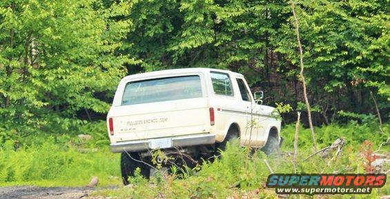 White Ford Bronco driving off-road, rear view. Text on tailgate reads 'FULLSIZEBRONCO.COM'