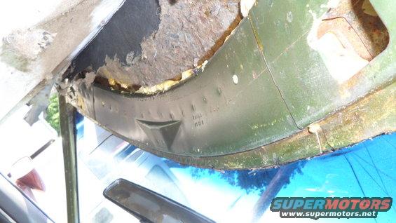 Green painted metal trim with visible rust and damage above a blue windshield