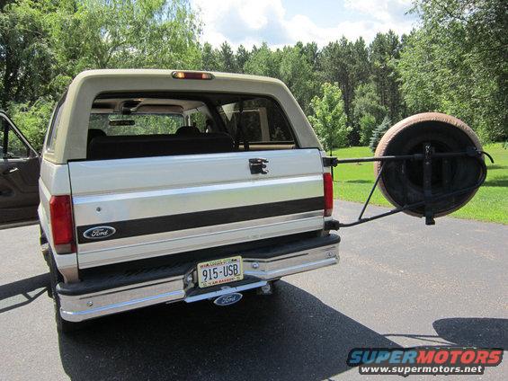Rear view of a white Ford Bronco with a spare tire mounted on the back. License plate reads 915-USB