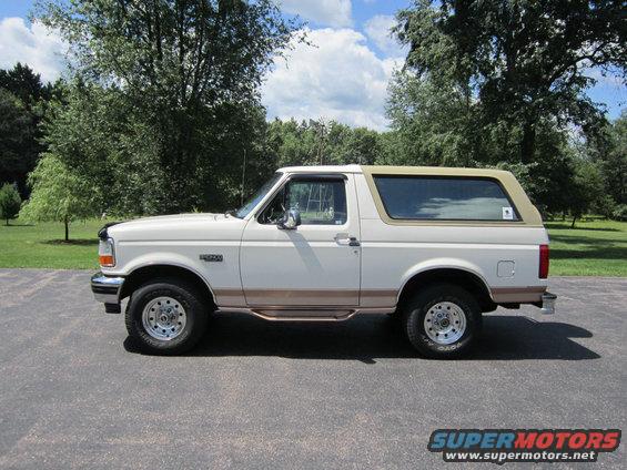White Ford Bronco with tan top and brown trim, parked on asphalt