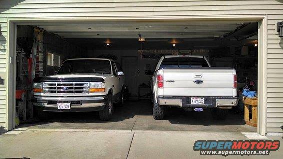 White Ford Bronco and white Ford F-150 parked in a garage