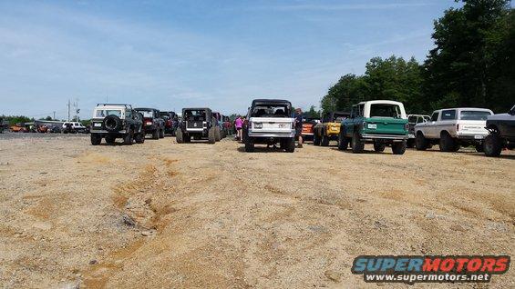 Several Ford Broncos and other 4x4s parked in a dirt lot under a blue sky