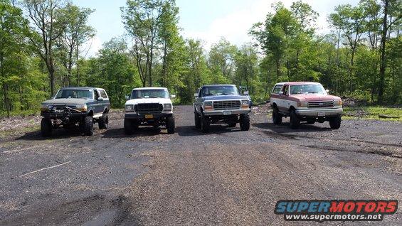 Four lifted Ford Broncos parked on a gravel lot, two-tone paint on the rightmost vehicle