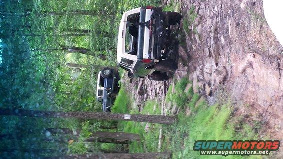 Two SUVs navigating a steep, rocky, wooded trail