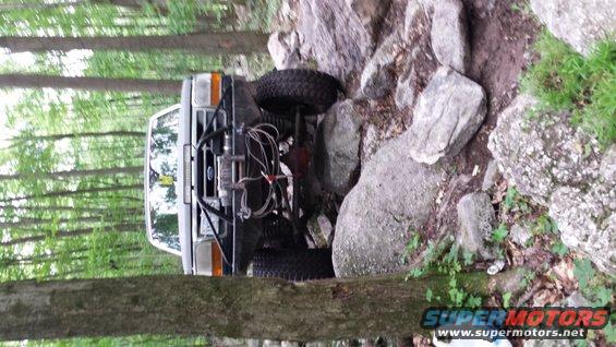 White Ford F-150 Bronco with winch and off-road tires navigating rocks