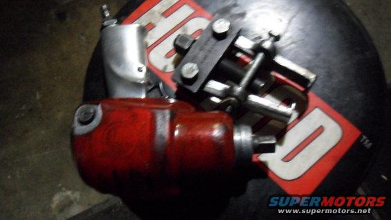 Red and silver automotive tools, possibly for engine work, resting on a black surface with a red logo