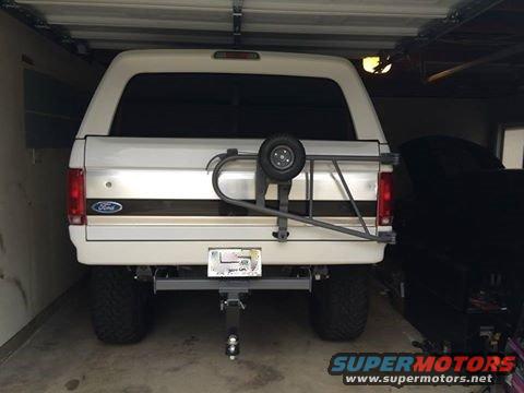 White Ford Bronco with spare tire on rear carrier, parked in garage