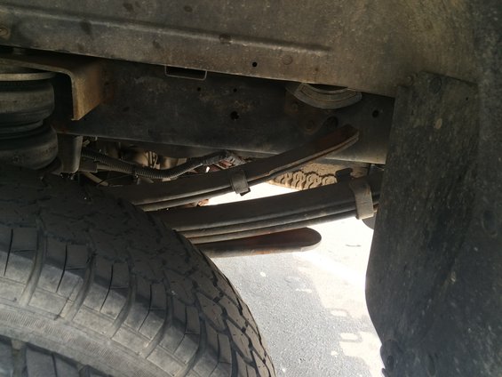 Underside of a truck showing leaf springs, tire, and frame