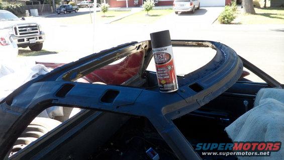 Spray can on car's A-pillar, interior visible. Ford truck in background