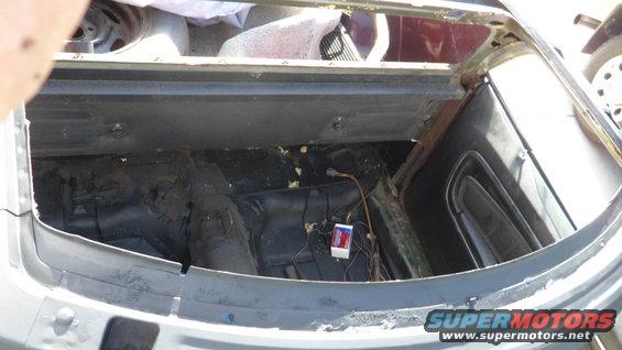 car's trunk area with exposed wiring and a small white box