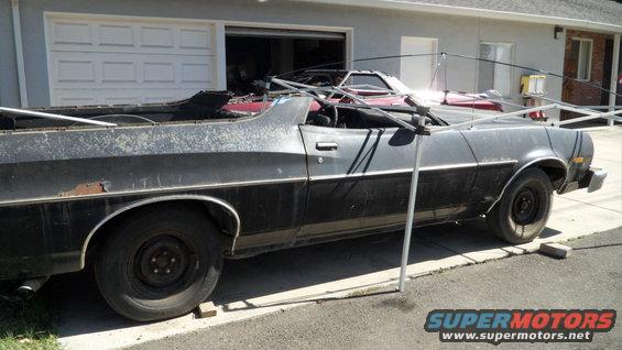 Side view of a black Ford Ranchero with a red car behind it in a driveway