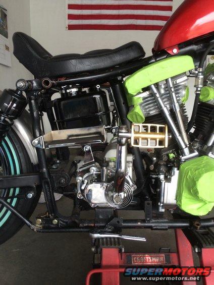 Motorcycle engine and frame with green tape on parts. American flag in background