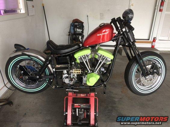 Red Harley-Davidson motorcycle on a red lift, with green engine covers and chrome fenders