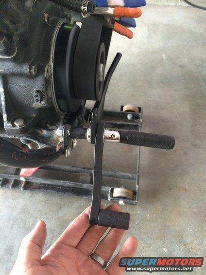 Motorcycle kickstarter lever being held by a hand near engine components