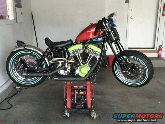 Red motorcycle on a red lift, with bright green engine covers and light blue tire stripes
