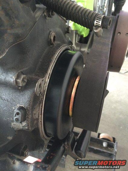 Black belt pulley assembly on a dark engine block with a ribbed hose above