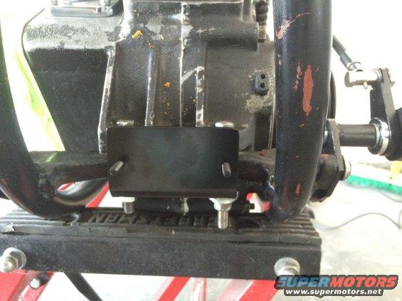 Close-up of a black metal bracket bolted to a motorcycle engine component